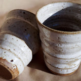 A close up shot of handmade white speckled cup with wide horizontal grooves by Sticky Earth Ceramics SG
