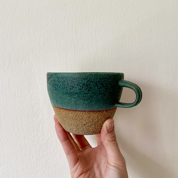 Hand holding a wide mouth ceramic mug